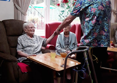 Singer holding hands with a resident in the lounge at Lulworth House