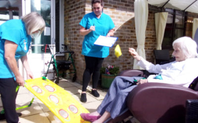 Resident throwing a bean bag into a target outside in the garden at Loose Valley Care Home