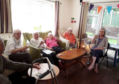 Residents at Lulworth House raising their glasses at the camera during a pub afternoon