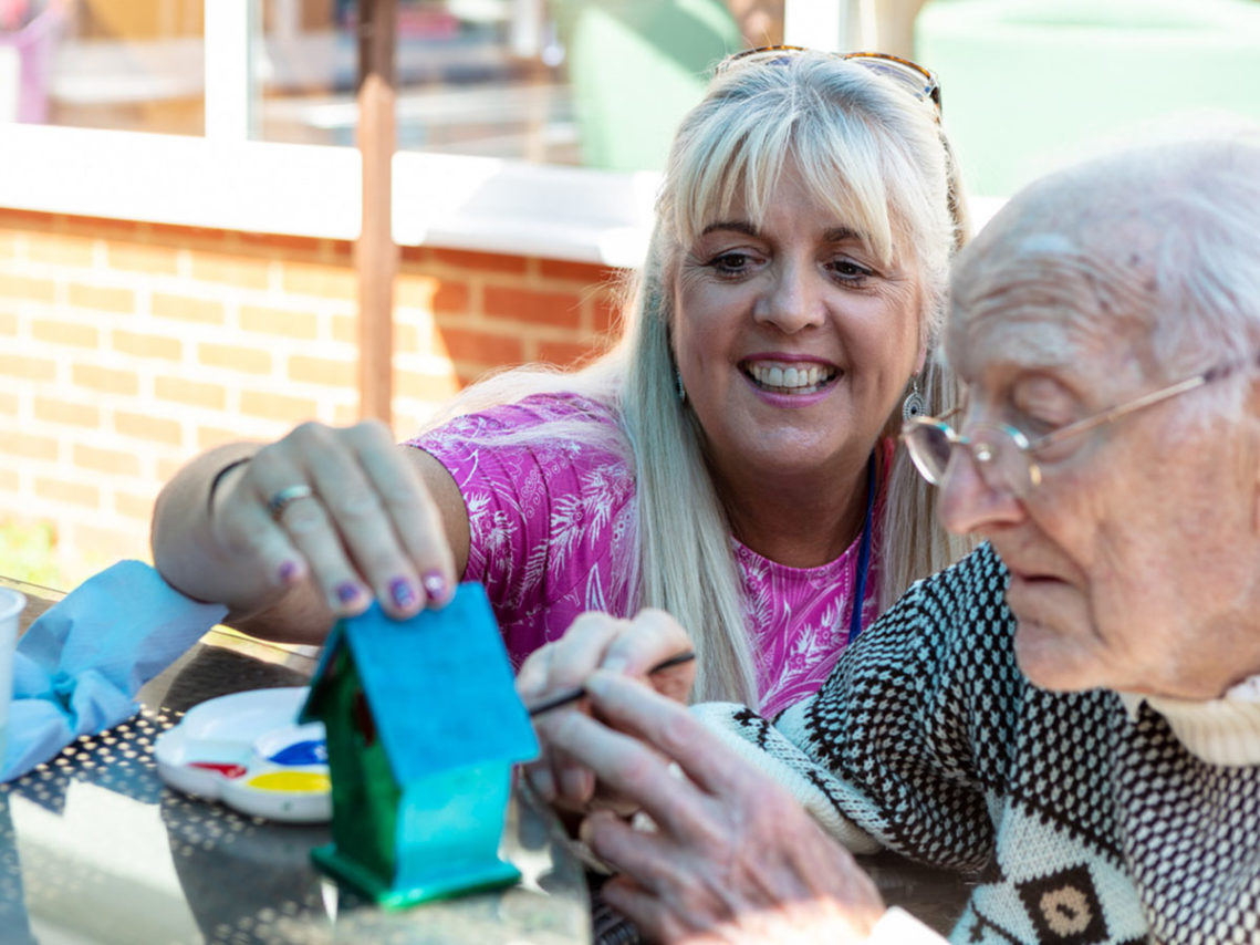 Christine Foster, Recreation & Well-Being Manager, with a resident painting a birdhouse together