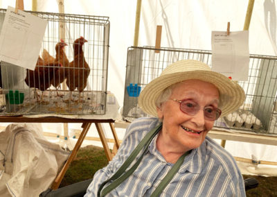 Lady resident smiling by a cage of chickens