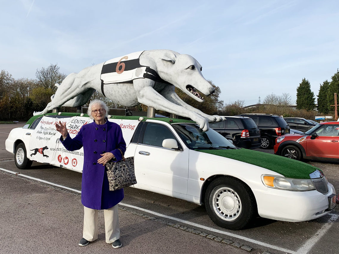 Lady resident from Lulworth House standing by a greyhound themed car at a dog racing stadium