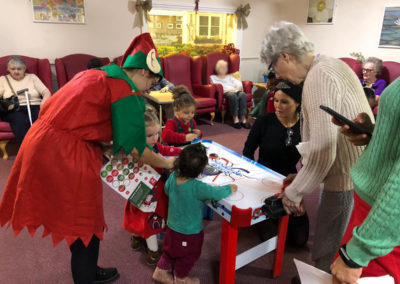 Residents, staff and preschool children playing table hockey together at Lulworth House