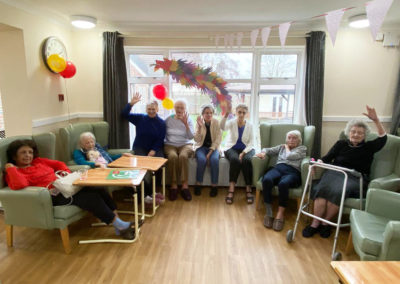 Sonya Lodge lady residents together in a lounge with a hand made Chinese Dragon collage displayed on the window