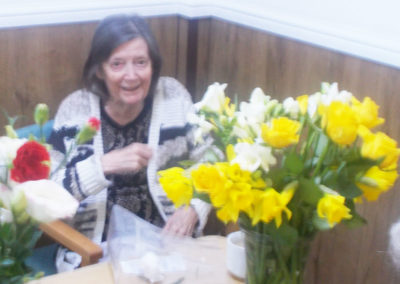 Resident sitting with a vase of bright daffodils