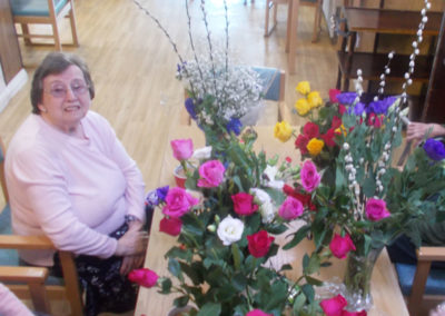 Resident sitting at a table with an array of flower vases filled with blooms