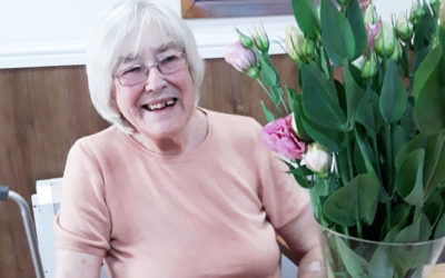 Lady resident at Sonya Lodge Residential Care Home smiling to camera with her flower arrangement