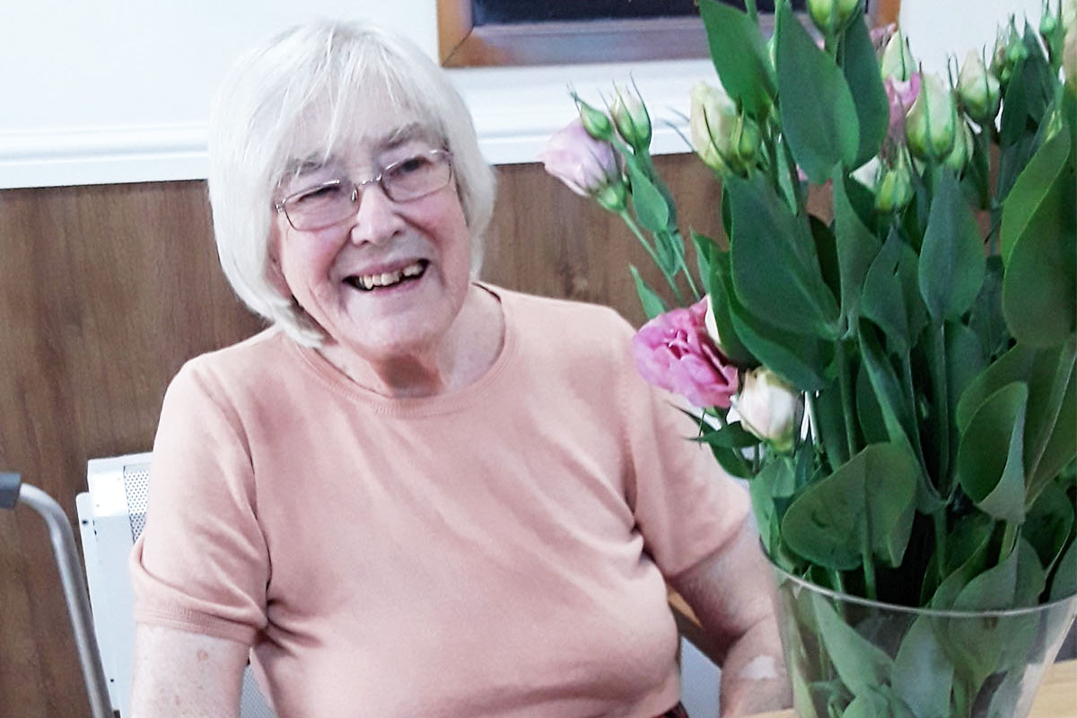 Lady resident at Sonya Lodge Residential Care Home smiling to camera with her flower arrangement