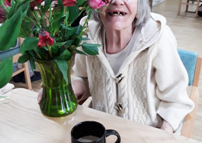 Lady resident at Sonya Lodge Residential Care Home smiling to camera with her rose arrangement