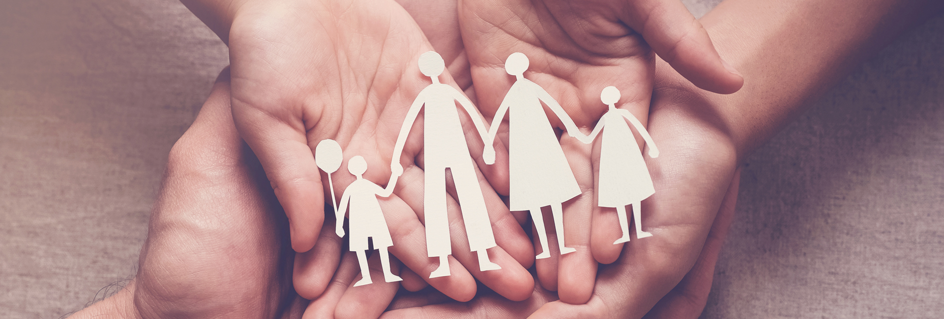 Adult and children hands holding paper family cutout, family home